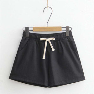 Black comfy shorts with adjustable drawstring and pockets, hanging on a hanger.