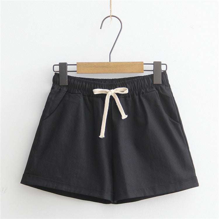 Black comfy shorts with adjustable drawstring and pockets, hanging on a hanger.