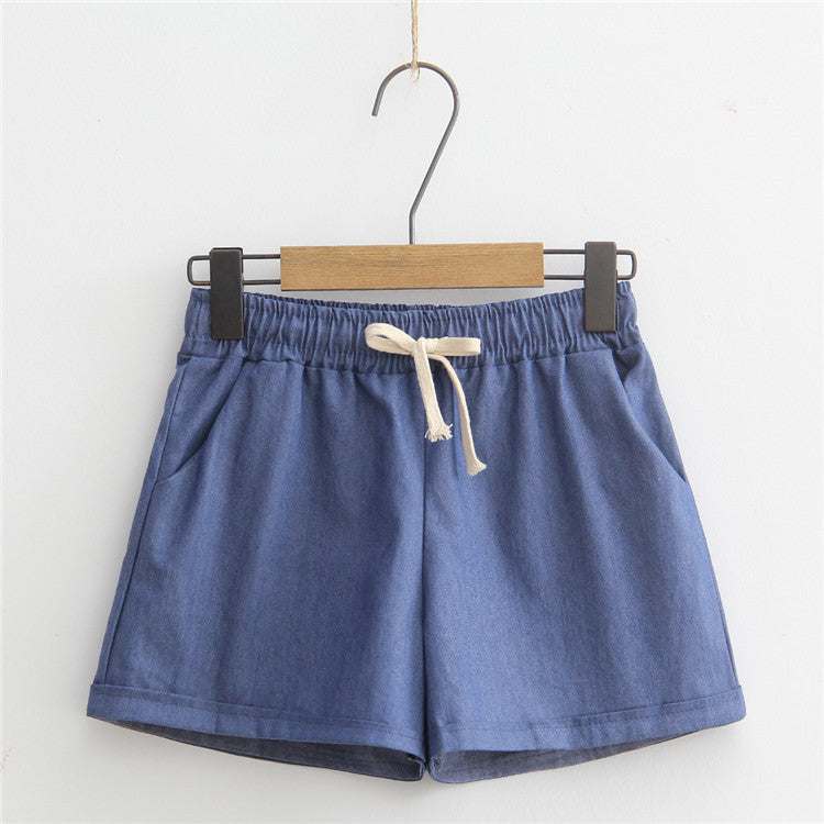 Blue Comfy Shorts with adjustable drawstring and pockets hanging on a wooden hanger.