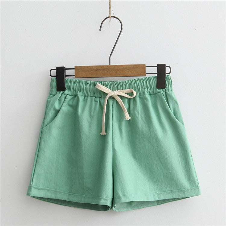 Mint green comfy shorts with adjustable drawstring and pockets, hung on a hanger.