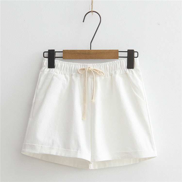 White comfy shorts with adjustable drawstring waist hanging on a hanger.