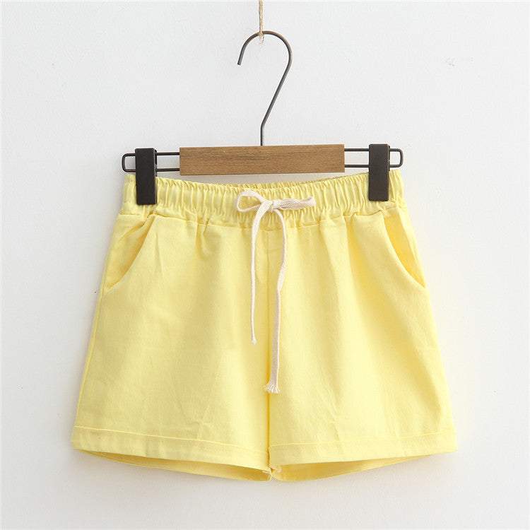 Yellow comfy shorts with adjustable drawstring waist, displayed on a hanger.