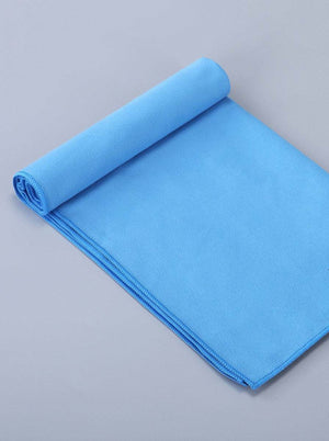 Blue premium sports towel rolled up on a flat surface showcasing its soft, quick-drying microfiber material.