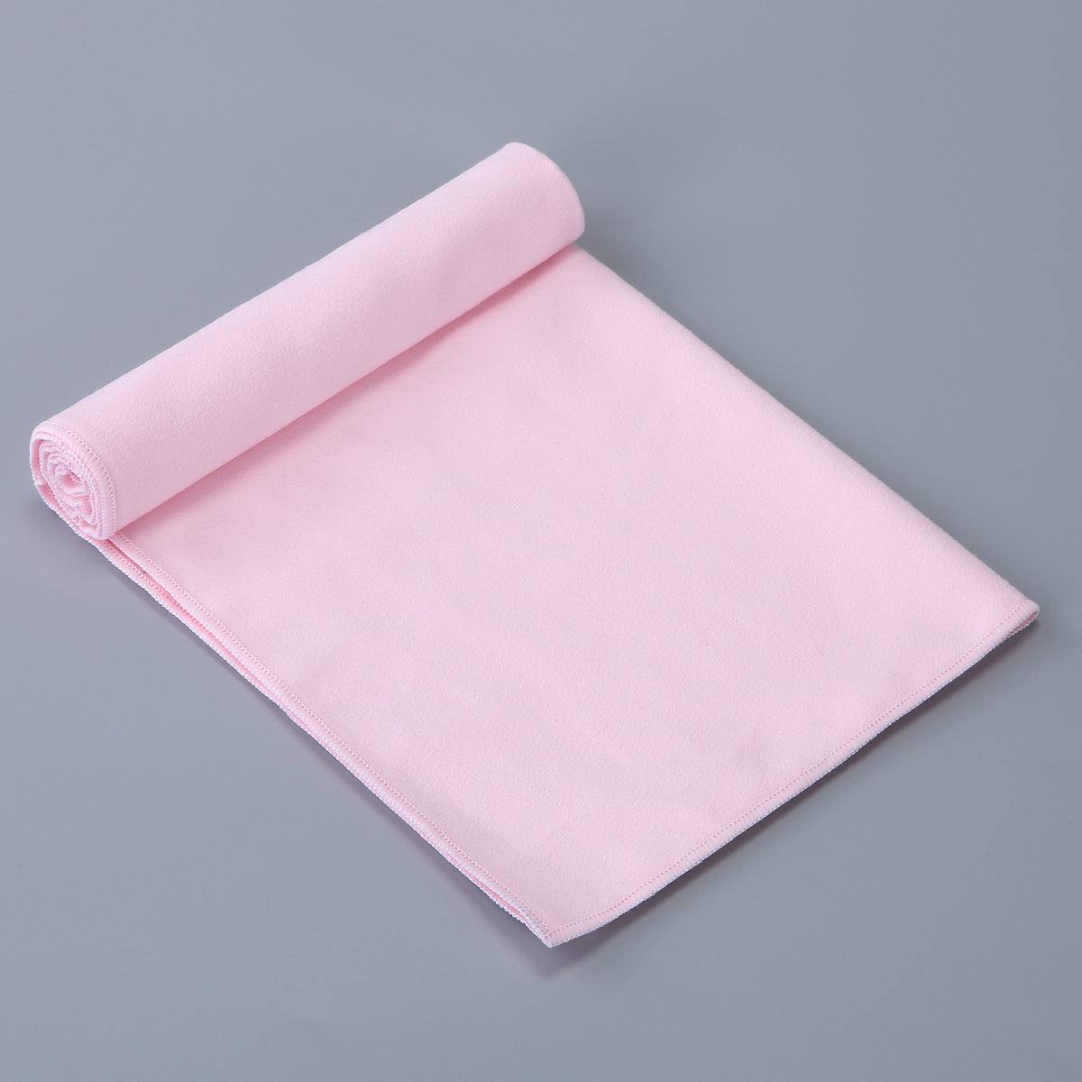 Pink rolled premium sports towel on gray background, made of soft microfiber blend.