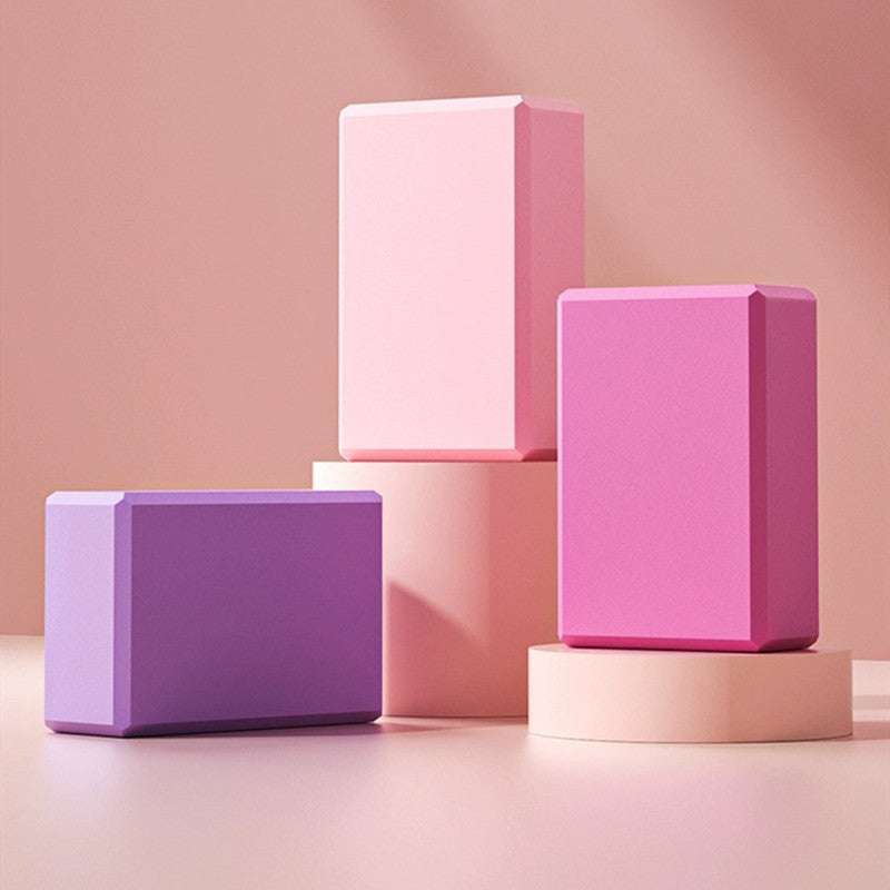 Colorful yoga blocks displayed on a pink background.